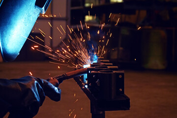 Worker at the factory welding steel structure. Welder and welding sparks, construction and metal...