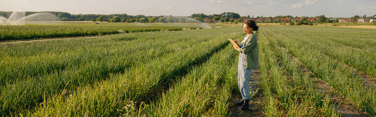 Female agronomist with clipboard standing on field . Agricultural occupation concept