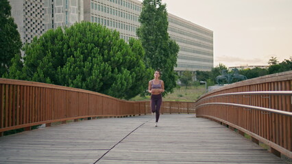 Active jogger running urban park. Satisfied athletic woman doing cardio training