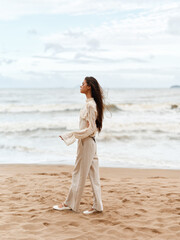 Fototapeta na wymiar Solitary Beauty: A Young Woman's Serene Stroll Along a White Sandy Beach at Sunset