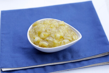Mashed banana in bowl on white background.