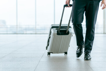 スーツケース・キャリーケースを持って出張に行くビジネスマン・海外出張・海外赴任・商社・貿易
 - obrazy, fototapety, plakaty