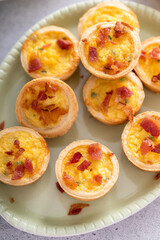 Obraz na płótnie Canvas Mini quiches with ham and cheese topped with crispy bacon