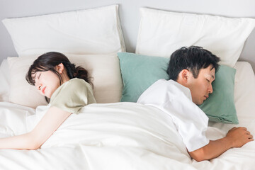 ベッドで眠る若い夫婦（快眠・安眠・熟睡）
