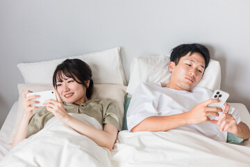 ベッドでスマホの動画を見る夫婦（睡眠の質・スマホぐせ・寝る前スマホ・寝不足）
