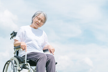 青空と車椅子に座る高齢者・シニア女性（介護・車椅子・おばあちゃん・デイサービス）
