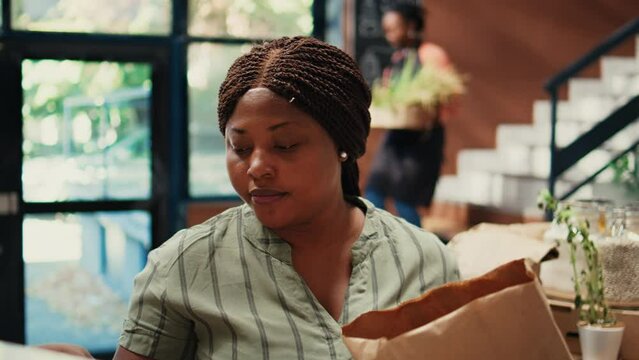 Buyer enjoying fresh smell of locally grown lemons from farm, smelling citric aroma and putting ecological fruits in a bag. African american client looking for homegrown goods. Tripod shot.
