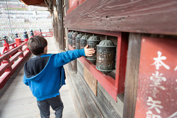 boy spinning japanese temple bells for good luck