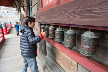 Boy spinning bells at a Japanese temple