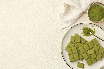 Pieces of tasty matcha chocolate bar and powder on white textured table, flat lay. Space for text