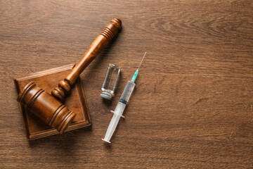 Law concept. Gavel, syringe and vial on wooden table, top view. Space for text