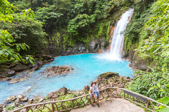 Young adult couple at Rio Celeste turquoise waterfall in the green rainforest, Costa Rica
