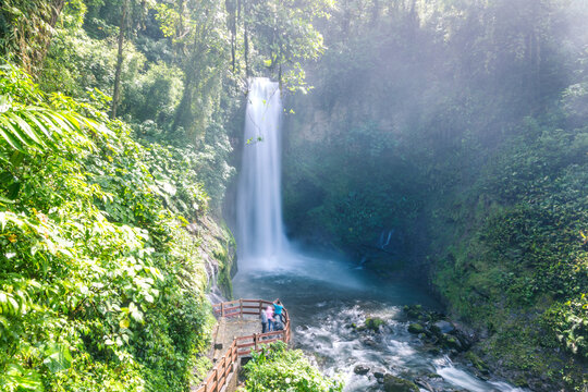 Couple looking at La Paz waterfall in the green rainforest of Costa Rica