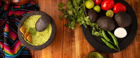 Obraz na płótnie Canvas Guacamole. Avocado dip with tortilla chips also called Nachos served in a bowl made with volcanic stone mortar and pestle known as molcajete. Mexican easy homemade sauce recipe very popular.