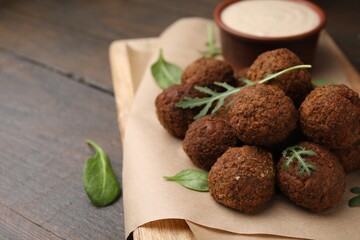 Delicious falafel balls, arugula and basil on wooden table, space for text