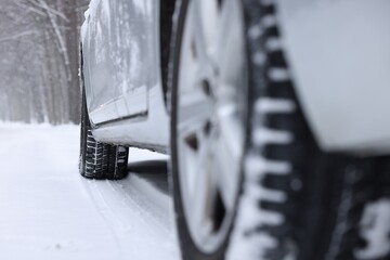 Car with winter tires on snowy road outdoors, closeup. Space for text