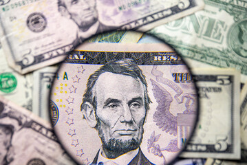 5 American dollar note with Abraham Lincoln face portrait magnified with a magnifying glass, on a...
