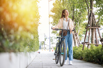 Happy female smiling walk down the street with her bike on city road, ECO environment, Lifestyle Asian young woman walking alongside with bicycle on summer in countryside outdoor, healthy travel