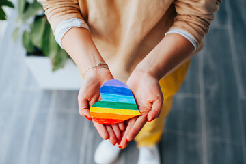 Photograph of woman's hands holding a hand drawn LGBTQ+ heart. Concept of people and lifestyles.