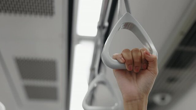Close Up Hands of Passenger Standing in Wagon, Confidently Holding Onto Grey Handle. Girl Holds the Handrail During the Journey on the Public Transportation Vehicle. Transport and People Concept