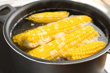 Cooking pot with boiling corn cobs, closeup