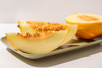 Plate with pieces of sweet melon on white background