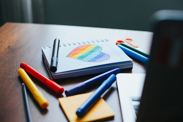 Photograph of notebook on wooden table with hand drawn LGBTQ+ heart. Concept of people and lifestyles.