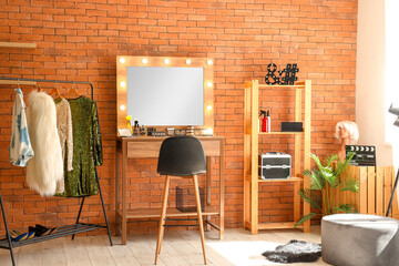 Stylish mirror, clothes rack and table with makeup cosmetics in dressing room