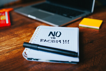 photograph of a notebook with the phrase "no to racism" on a table. 