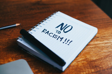 photograph of a notebook with the phrase "no to racism" on a table. 