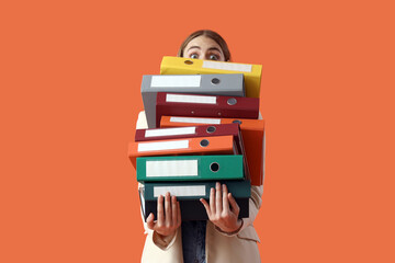 Young businesswoman with document folders on orange background