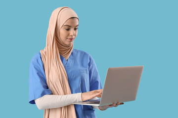 Fototapeta na wymiar Muslim medical intern using laptop on blue background