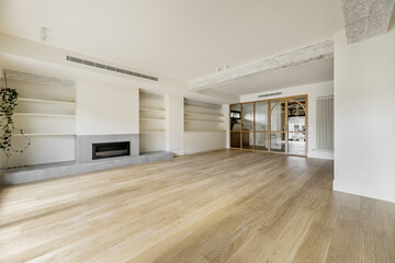 A large empty living room with a wall with a fireplace and plaster shelves