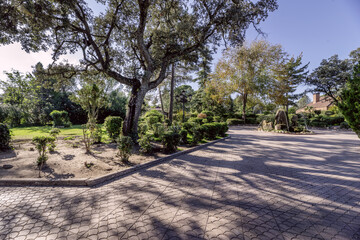 A fountain inside a roundabout of a paved walkway inside an extensive property with a single-family home - obrazy, fototapety, plakaty