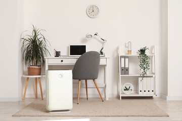 Interior of light office with air purifier and workplace
