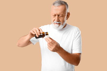 Old man with sore throat holding cough syrup on beige background