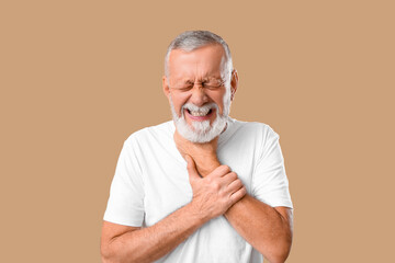 Ill old man with sore throat on beige background