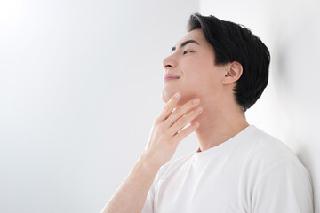 頬を触るアジア系（日本人）男性 爽やかな脱毛やスキンケアのイメージ...