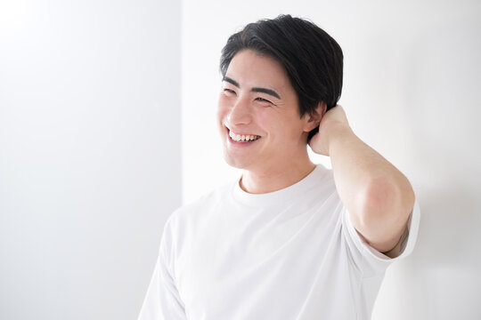 髪を触るアジア系（日本人）男性 爽やかな脱毛やスキンケアのイメージ　照れる