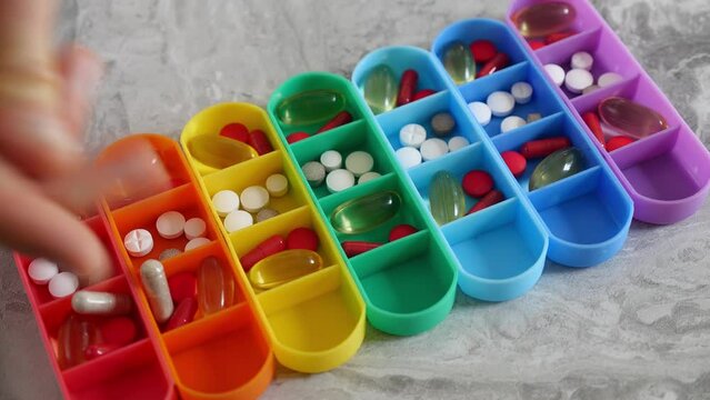 A woman fills a weekly pillbox with medicines