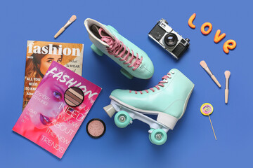Composition with pair of vintage roller skates, photo camera, magazines and cosmetic products on blue background