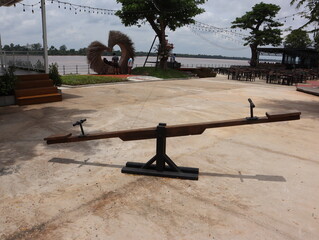 Wooden see-saw for children on a concrete terrace on the riverbank
