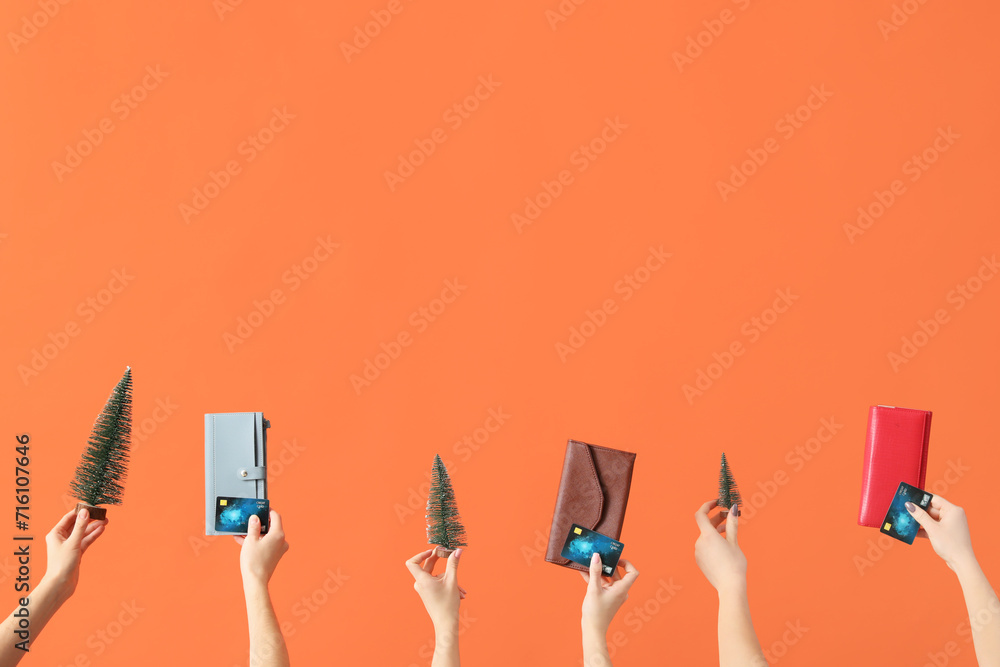 Wall mural Women with credit cards, toy Christmas trees and wallets on orange background