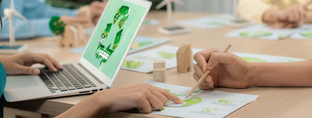 Recycle sign displayed on green business laptop while business team presenting green design to...