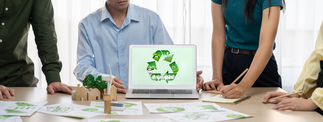 Recycle sign displayed on green business laptop while business team presenting green design to customer. ESG environment social governance and Eco conservative concept. Closeup. Delineation - obrazy, fototapety, plakaty