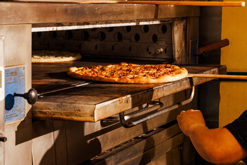 Pulling a pizza out of the oven