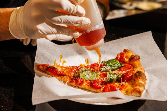 Drizzling hot honey on a pizza slice