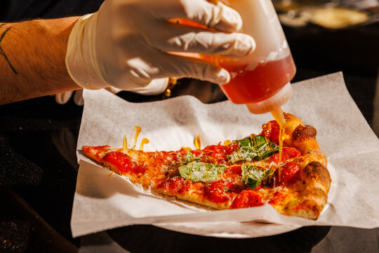 Drizzling hot honey on a pizza slice