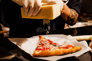 Shaving fresh cheese on a pizza slice
