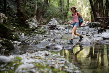 Mid Adult Woman hiker Enjoying a Hike over Water Stream in a Forest